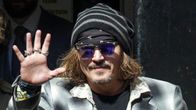 Johnny Depp hymyilee ja vilkuttaa.
