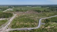 Aerial view of scrubby fields, a forest and a few roads.