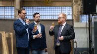 Jere Räisänen, Jouko Juvonen ja Joonas Hänninen kilistelevät juomia konepajalla. 