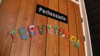 Ruskeassa puuovessa on kyltti, missä lukee perheosasto. Sen alapuolella on värikkäistä kirjaimista kirjoitettu sano tervetuloa.
