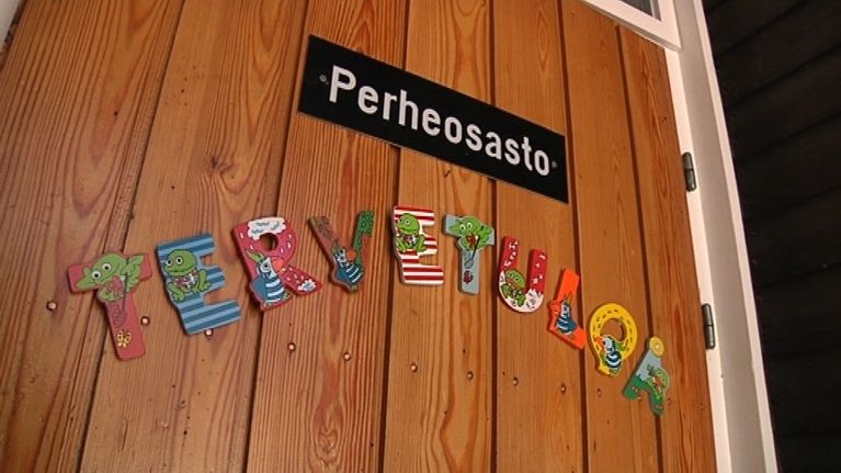 Ruskeassa puuovessa on kyltti, missä lukee perheosasto. Sen alapuolella on värikkäistä kirjaimista kirjoitettu sano tervetuloa.