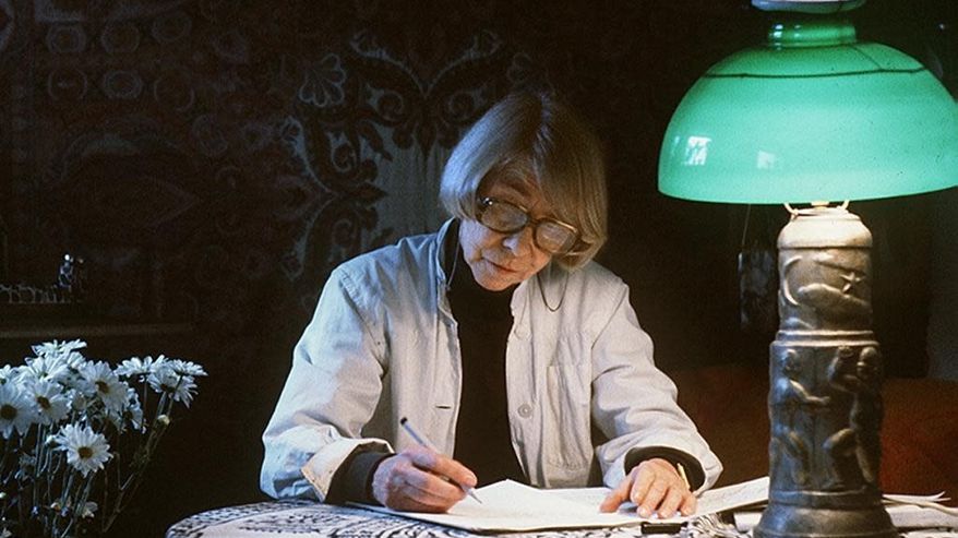 Kirjailija ja taiteilija Tove Jansson kirjoittaa pöydän ääressä.