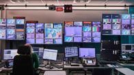 Nainen ohjaamossa edessään paljon näyttöjä, joissa tv-uutiset.