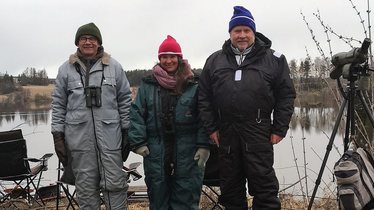 Linnunlaulujen aamun asiantuntijat seisovat vierekkäin haalareissaan tyytyväisinä. 