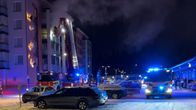 Kerrostaloasunnosta nousee savua pimeässä illassa. Maassa useita paloautoja.