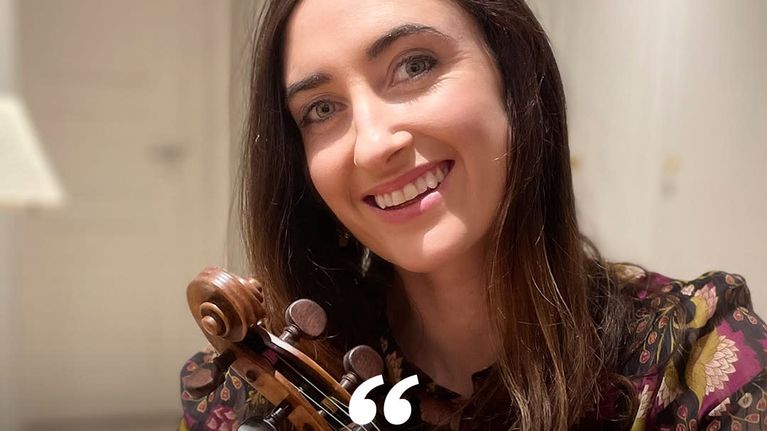 A woman with a violin looking into the camera. On top of the image the text "I love the fact that every time RSO plays a concert, the audience doesn't just consist of those people we see sitting in the concert hall, but extends out to every corner of Finland, be it through television, radio or internet" Pauline, 1st Violin Player.