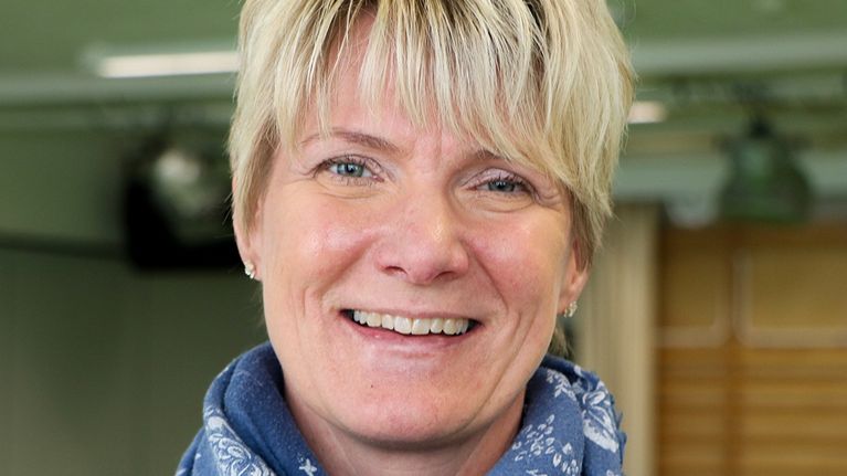 Kvinna i scarf ler mot kameran.