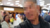 En person med mörk väst håller en röd läskburk. Mannens ansikte är blurrat.