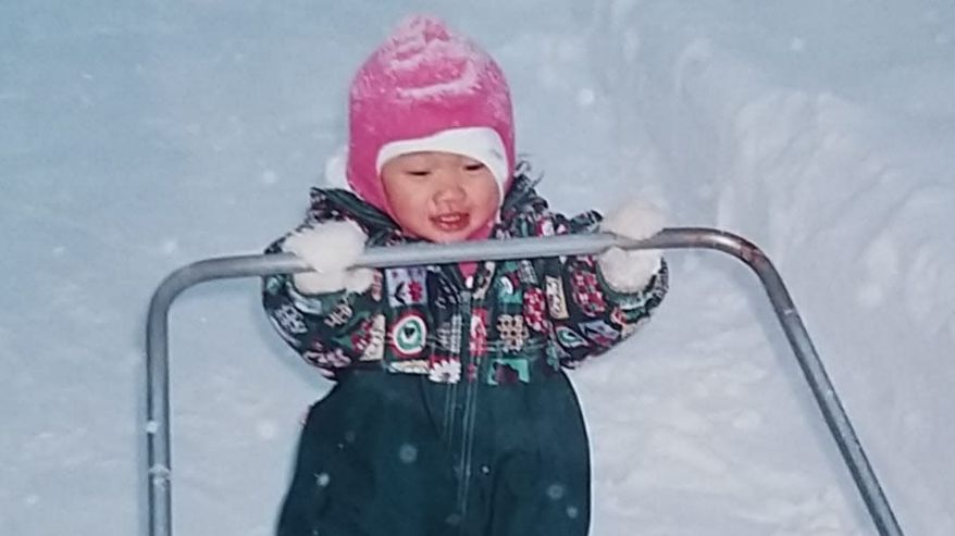 Saara Keskitalo taaperona talvihaalarissa työntämässä lumikolaa.