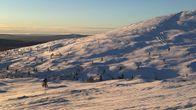 Lumisen tunturin luonnonvarainen rinne auringonlaskun aikaan.