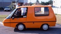Oranssi Finnvan-sähköauto parkkeerattuna asfalttikadun varteen.