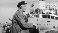 Mies istuu satamassa
