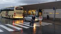 En buss står utanför Vasa flygplats. Två personer med resväskor går över vägen. Det är blött på marken.