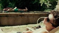 Elio (Timothée Chalamet) solar utomhus, i bakgrunden ser man Oliver (Armie Hammer) som också solar.