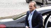 Medvedtšuk  kävelee isolta mustalta autolta tummassa puvussa ja vaaleansinisessä kauluspaidassa ilman kravattia.