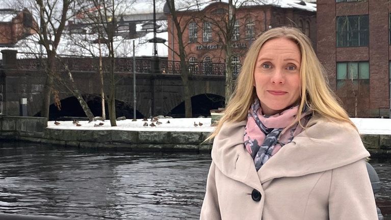 Marika Puolimatka seisoo veden äärellä ja katsoo kohti kameraa.