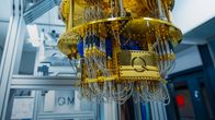 A large cylindrical gold-coloured piece of machinery with many wires attached hangs from a ceiling.