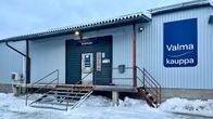 Talvinen kaupparakennus, jossa sininen seinä ja sisäänkäynnin edessä rautaiset portaat, joiden ympärillä on lunta.