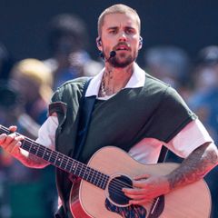 Justin Bieber sjunger och spelar akustisk gitarr på scen.