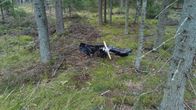 A pile of metal wreckage from a crashed drone lying on the ground in a forest.