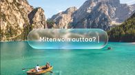 Pariskunta soutaa turkoosissa vedessä vuoria taustalla.
