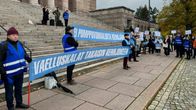 Ihmisiä eduskuntatalon portailla, välissä banderollit joissa tekstit "ei pumppuvoimaloita kemijärvelle" ja "vaelluskalat takaisin Kemijokeen".