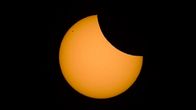 An image of a crescent-shaped orange sun with a black background.