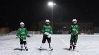 Barn som spelat bandy står i gröna tröjor på isen. 