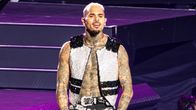 Chris Brown i svarta byxor och en glittrig öppen väst på en scen. Han har bar överkropp under västen och håller i en mikrofon.