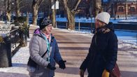 Två personer går på en snöig gata, vänder sig mot varandra och samtalar. I bakgrunden syns träd och Åbo domkyrka.