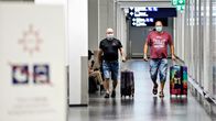Kaksi matkustajaa kävelee matkatavaroidensa kanssa Helsinki-Vantaan lentoasemalla 7. elokuuta 2020. Kasvojensa edessä heillä on kasvomaskit.
