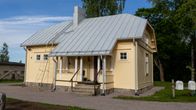 En liten ljusgul eller beige trästuga.