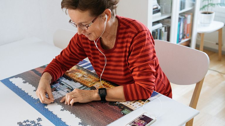 Woman listening Yle Areena and making a puzzle.