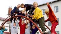Oppilaita välitunnilla koulun pihalla kiipeilytelineessä.