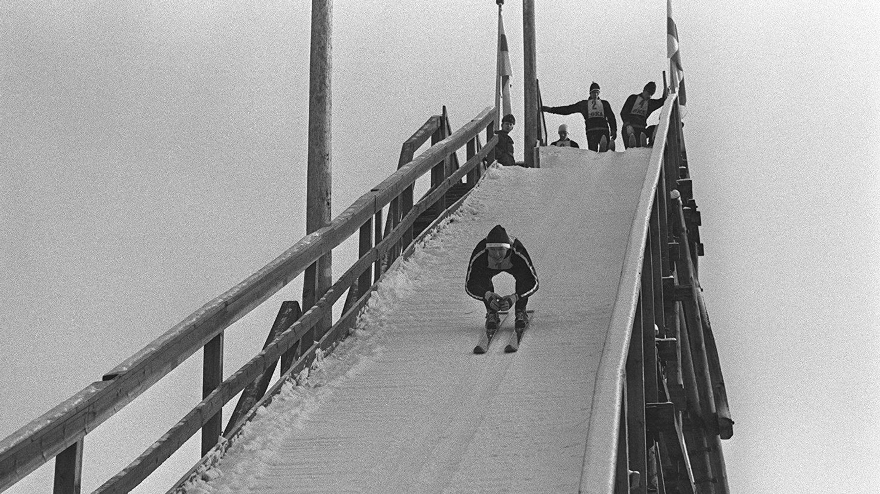 Mäkihyppääjä laskee puisen hyppyrimäen vauhdinottotornista (1960-luku)