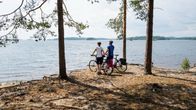 Two cyclists admire a lakeview.