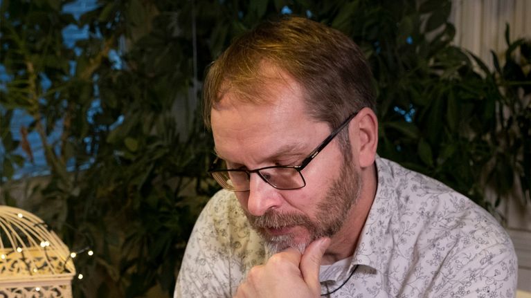 Mika Koivunen istuu pöydän äärellä ja katselee Kansa taisteli -lehteä.