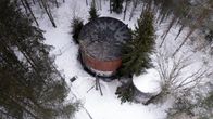 Drone-kuva puiden keskellä sijaitsevasta vesitornista, jonka katto on palanut. 