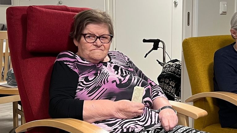 Ulla Niittyvuopio istuu punaisella nojatuolilla ja katsoo kameraan.