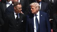 Finnish president Alexander Stubb and US president Donald Trump stand and talk to each other.