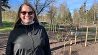 Nainen aurinkolaseissa hymyilee istutettujen kasvien vieressä.