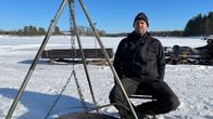 Mustapipoinen mies istuu järven jäällä jakkaralla. Taustalla on moottorikelkka.