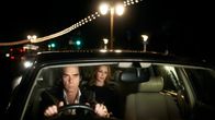 Nick Cave ajaa autoa, Kylie Minougue istuu kyydissä. Kuva dokumenttielokuvasta Nick Cave: 20 000 päivää maan päällä.