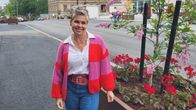 En kvinna som står intill en blomlåda på en gata i stan vid torget.