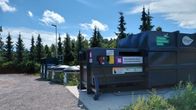 Jäteastioita rivissä hiekkakentän laidalla.