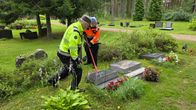 Kaksmi miestä nostaa työkalujen avulla kaatunutta hautakiveä.