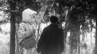 Avaruuspukuinen mies juttelee naisen kanssa kylänraitilla.