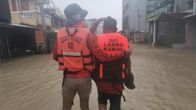 Kaksi miestä kahlaa veden peittämällä kadulla. Heillä on yllään pelastusliivit. Toisen miehen liiveissä lukee Coast Guard eli rannikkovartiosto.
