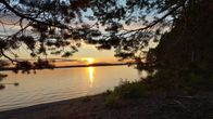 Aurinko laskee kesällä järvimaiseman taakse Kuopion Kallavedellä.