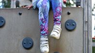 A child's feet dangling over a climbing wall. 